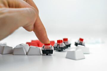 Mechanical keyboard switch on a white background. The person presses the keyboard switch with his...