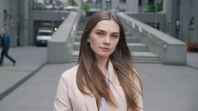 Young woman manager in formal outfit looking to camera outside business district. Portrait of pretty businesswoman standing outdoors at downtown.