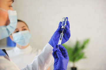 Caucasian woman is preparing the vaccine for the patient waiting nearby at the medical center