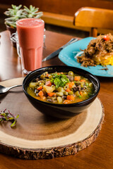 Delicious Soup Bakery Green Spinach Vegetables Carrot Sausage Cream in a black bowl on a wooden table