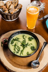 Delicious Soup Bakery Green Spinach Vegetables Carrot Sausage Cream in a black bowl on a wooden table