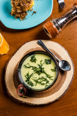 Delicious Soup Bakery Green Spinach Vegetables Carrot Sausage Cream in a black bowl on a wooden table