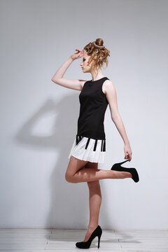 Fashion portrait of a girl in a small short dress with a creative hairstyle on a light background.