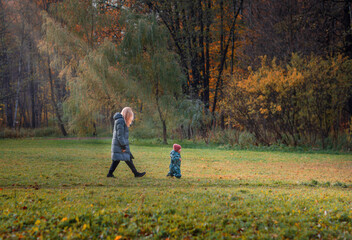 family walking in the park in autumn, autumn landscape, baby running away from mom, parental leave