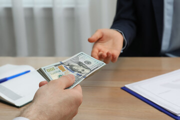 Cashier giving money to businessman at desk in bank, closeup