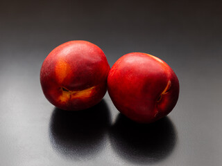 Juicy red nectarines with velvety skin on a dark background