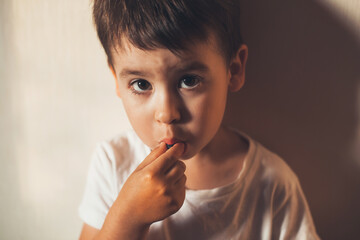 Close up photo of a small kid eating berries at home looking at camera