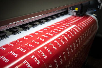 A machine for large-format printing, prints stickers with the inscription sale for holidays in...