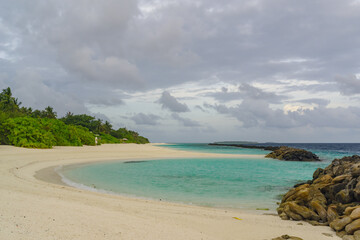 Snow-white and wet sand on the ocean, crystal clear water and bushes on the edge, a photo taken in the Maldives