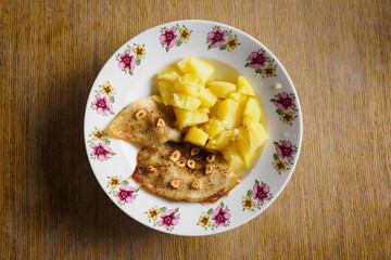 Fish fillet fried in butter and garlic with potatoes on a plate.