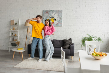 smiling young couple in casual clothes dancing in modern loft