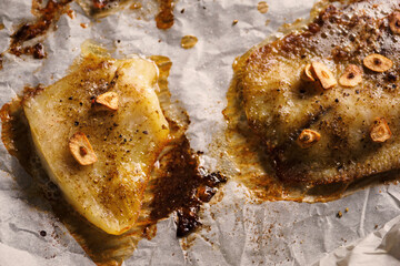 Fish fillet fried in butter and garlic on baking paper.