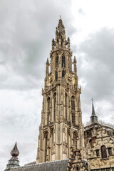 Fototapeta na wymiar bottom view of the gothic Cathedral of Our Lady in Antwerp and the fountain against the sky on a gloomy day and at sunset