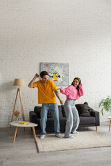 positive young couple in casual clothes dancing together in living room
