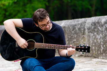 Young man playing guitar sitting on the bridge