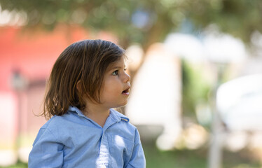 A little boy, about 2.5 years old, is looking aside and staring at something and he looks amazed from what he is seeing.