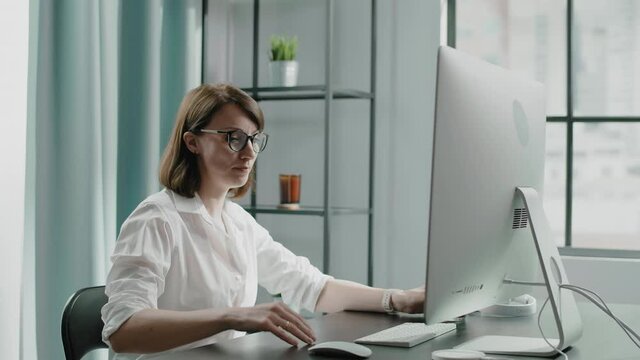 Woman in blouse with cup of coffee sits down at table