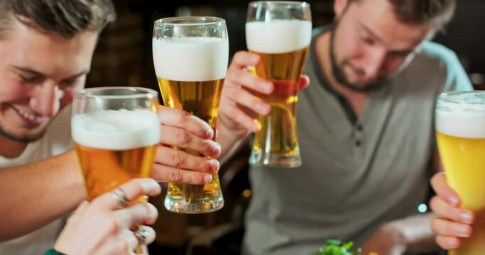 Slow motion close up of happy young friends having fun together drinking beer and clinking glasses in a pub. Concept of friendship, holidays, celebration