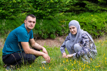 Young muslim couple squatting on grass and looking to the camera
