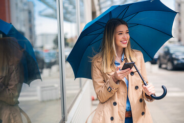Happy businesswomen smiling under blue umbrella