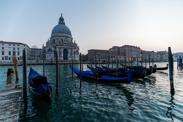 Fototapeta na wymiar Venetian gondola at sunset, gondolas moored in Venice with Santa Maria della Salute basilica in the background, Italy