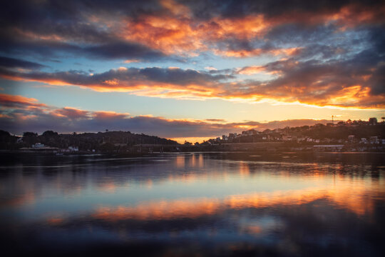uma foto do podo sol na hora dourada, com um lago espelhado e o c&eacute;u com bastante drama.