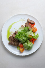 Menu for the restaurant: salad with beef, lettuce and cherry tomatoes with olive oil, lime and spice dressing.