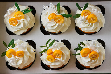 Festive muffins with cream cheese cream and citrus filling. Confectionery for the holiday. Dessert decorated with kumquat and tangerine, packed in a gift box.