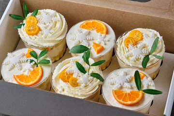 Holiday trifles with cream cheese cream and citrus filling. Confectionery for the holiday. Dessert decorated with kumquat, tangerine and green pistachio leaves, packed in a gift box.