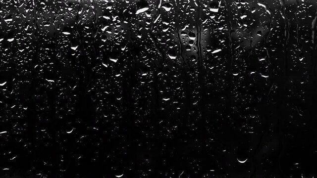 Drops on glass on a dark background. Raindrops from the copy space. Rain outside the window black background