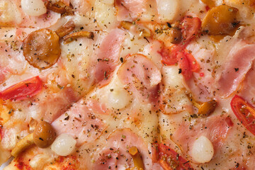 Pizza with tomatoes, bacon, pickled onions, honey mushrooms, mozzarella cheese, spices and tomato sauce. A closeup of a pizza.