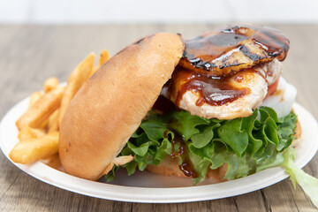 Teriaki chicken sandwich glazed with sweet sauce and pineapple served with onion rings and french fries