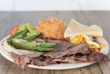 Grilled carne asada steak meat, hot and served with rice and cooked jalapeno peppers