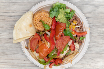 Overhead view of chicken fajitas, hot off the grill piled high with vegetables and large chunks of meat on a plate with tortillas