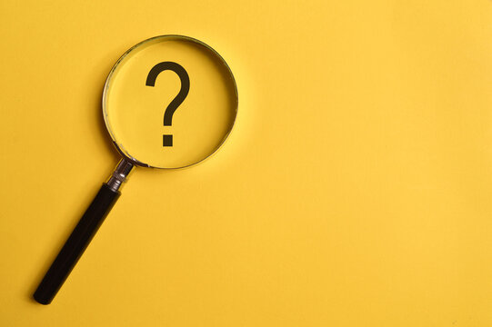 Top view of magnifying glass and question mark isolated on yellow background.