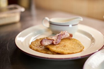 the chef prepares potato pancakes with fried bacon slices