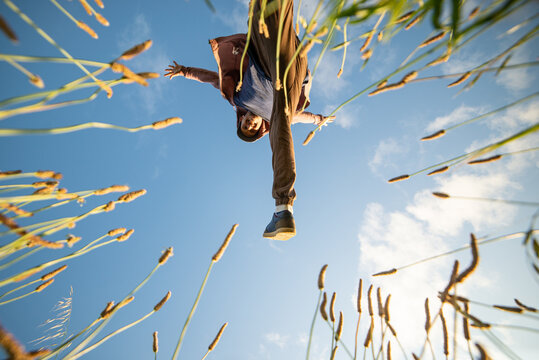 Bottom View of a Young Man Jumping Through grass in a Sunny Day