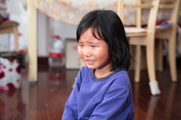 Aggrieved four-year-old girl sitting on the floor and crying