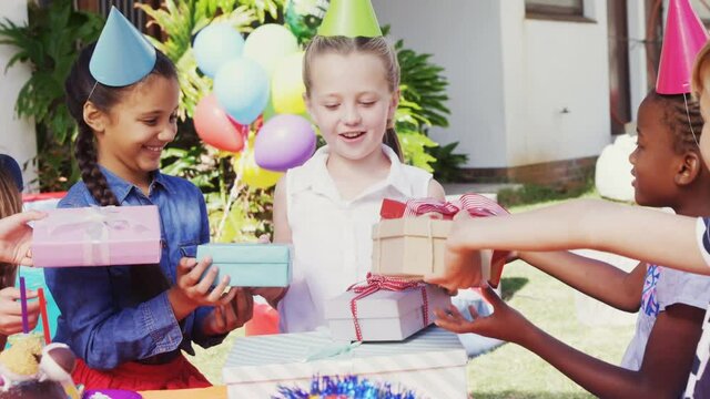 Animation of red specks over birthday presents and children having fun at party
