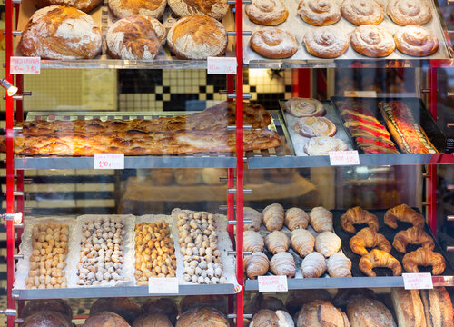 Spanish bakery showcase with freshly baked bread and various appetizing sweet confectioneries. Price tags with product names in Catalan.