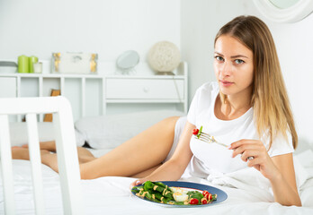 Obraz na płótnie Canvas Attractive girl in underwear having healthy breakfast in her bed