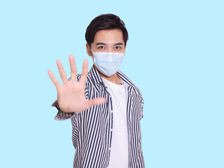 young man wears a protective medical mask to prevent COVID-19 infection and showing the stop gesture