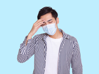 young man feel uncomfortable touching his head and wearing a protective medical mask.