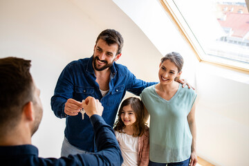 Fototapeta na wymiar Happy family with children buying property or receiving keys of new home from real estate agent. Moving into new apartment.