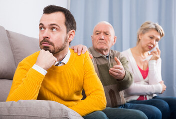Elderly grandfather talking seriously and instructs his grandson at home