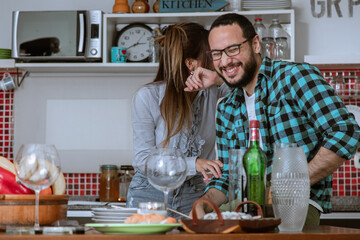 Pareja de jóvenes tienen todo preparado en la cocina para recibir amigos a cenar