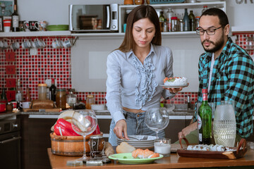 Pareja de jóvenes tienen todo preparado en la cocina para recibir amigos a cenar