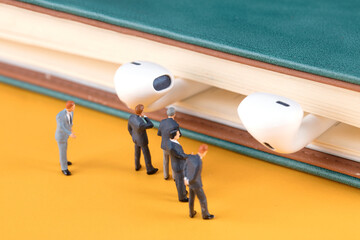 A group of business men’s miniature doll models are studying the headsets on the books