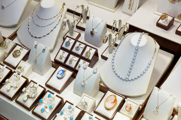 Collection of precious metals jewellery with precious stones displayed for sale on shelves of jewelry boutique
