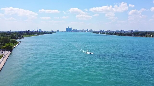 Boat travels down the Detroit River with city in the background